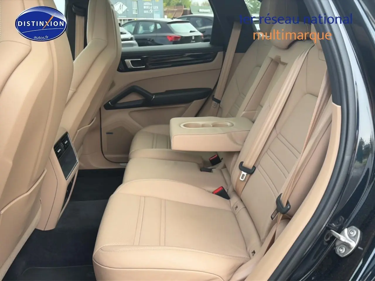 Vue côté droit de l’habitacle arrière beige d’un Porsche Cayenne 2023 avec accoudoir central et porte ouvert.