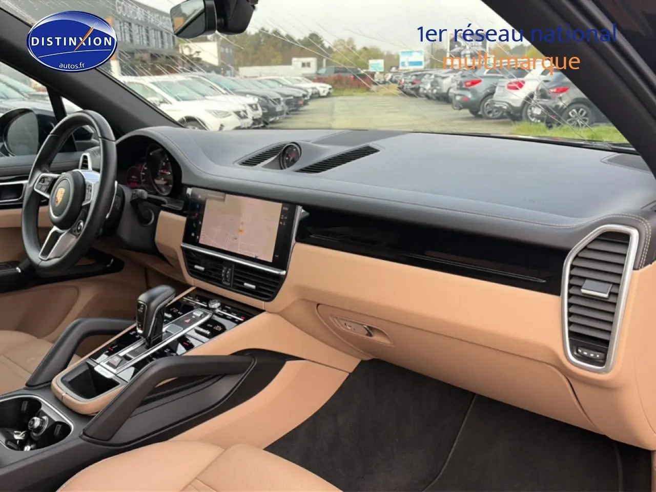 Vue intérieure côté passager du tableau de bord beige et noir du Porsche Cayenne 2023 avec écran tactile et volant cuir.
