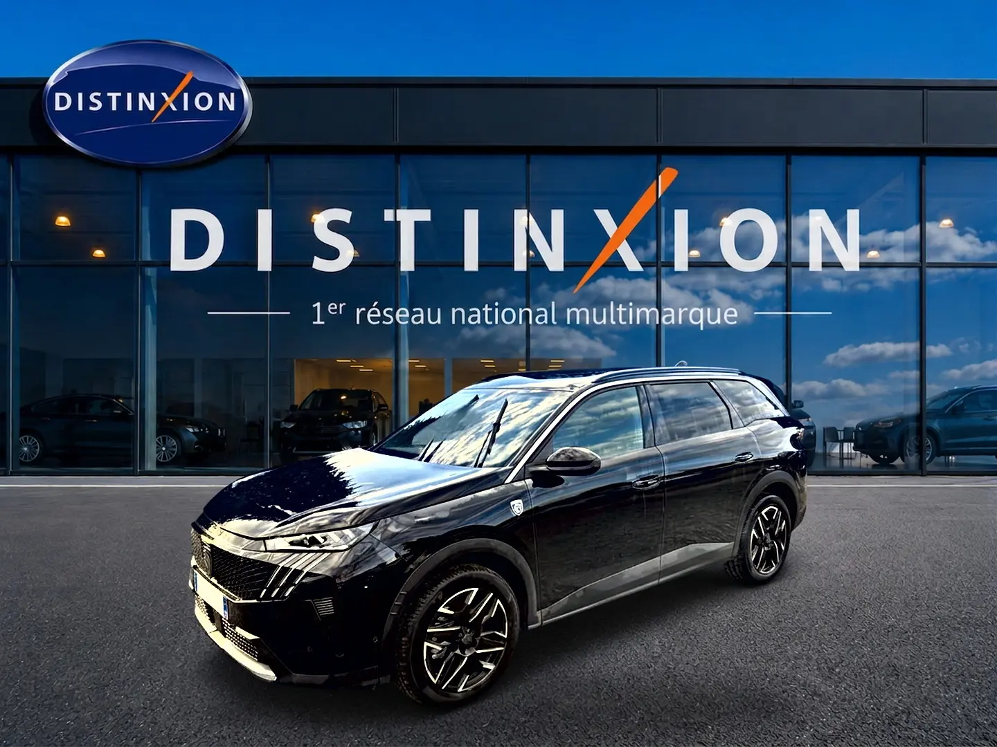 Peugeot 5008 Hybrid 145 GT noir en 3/4 avant droit, avec jantes alliage et vitres surteintées devant un showroom Distinxion.