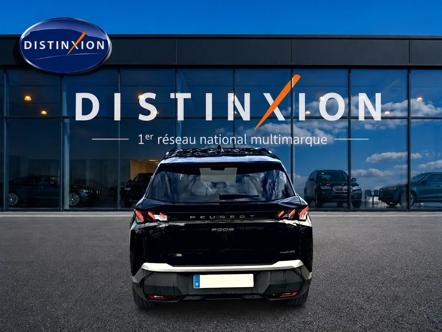 Vue arrière d'un Peugeot 5008 Hybrid 145 GT noir garé devant une vitrine avec logo Distinxion.