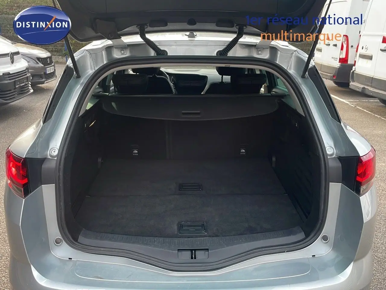 Coffre ouvert en vue arrière d'une Renault Mégane Break gris Highland Metal, montrant un espace de chargement spacieux et noir.