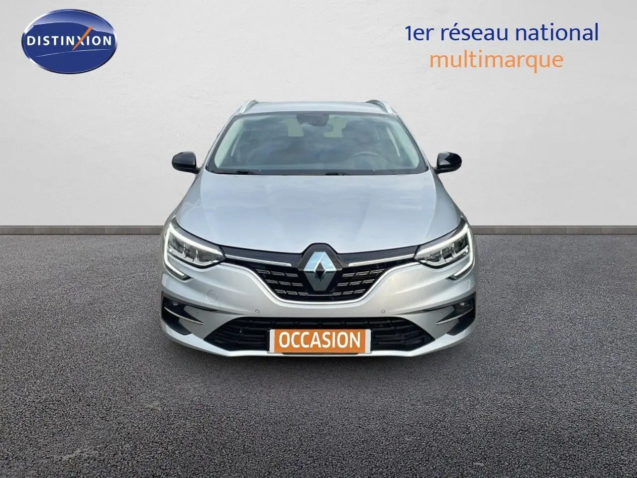 Vue frontale d'une Renault Mégane Break gris Highland Metal avec calandre noire et phares LED allumés.