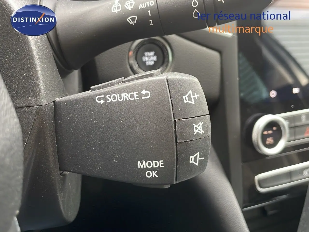 Gros plan sur la commande au volant gauche de la Renault Mégane Break gris Highland Metal, avec bouton source et réglage volume.