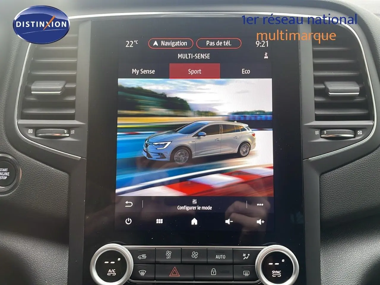 Écran tactile montrant une Renault Mégane Break gris Highland Metal en 3/4 avant sur circuit en mode Sport.