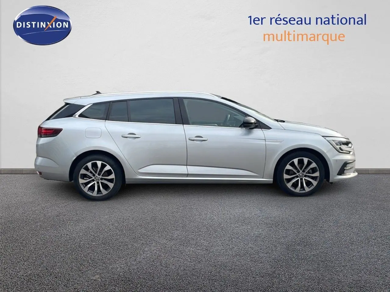 Profil latéral droit d'une Renault Mégane Break 2024 gris Highland Metal avec jantes alliage bicolores.