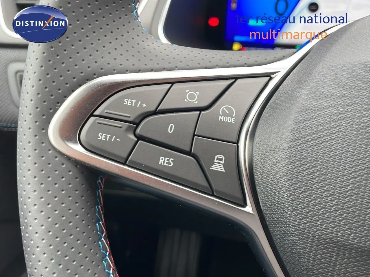 Gros plan sur les commandes de régulateur de vitesse au volant perforé d'une Renault Symbioz gris cassiopée.