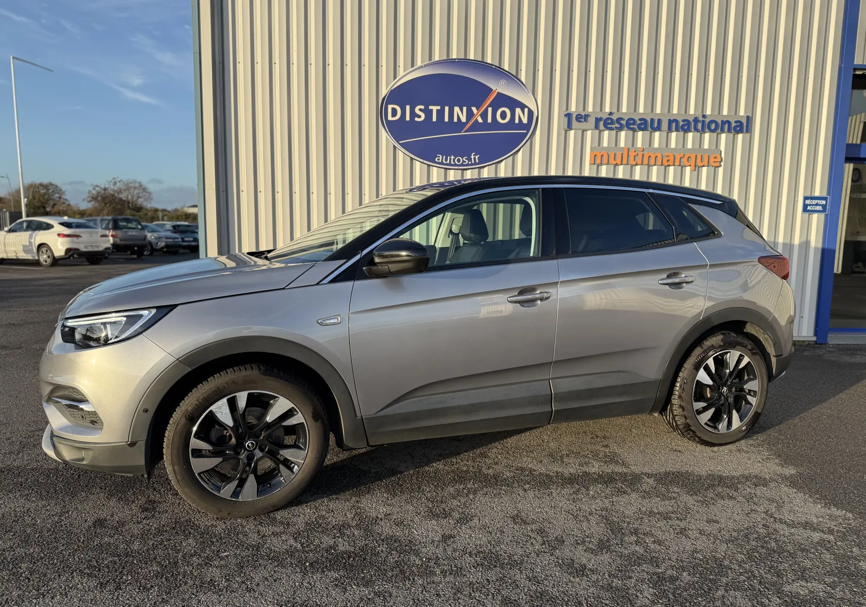 Opel Grandland X gris quartz vu de profil côté gauche, avec jantes noires bicolores et toit noir contrasté.