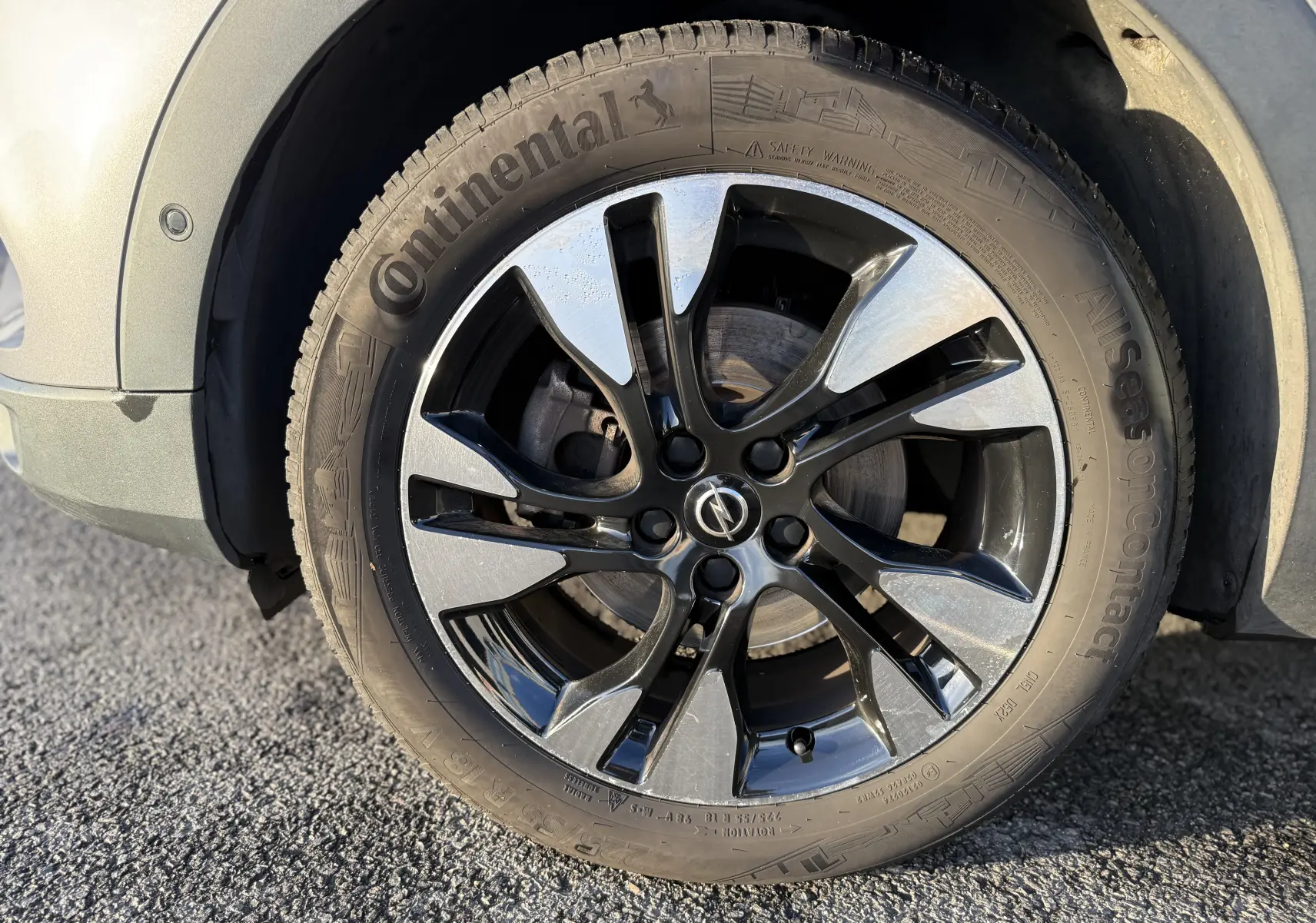 Gros plan sur la jante noire et argentée avec logo Opel d'un Opel Grandland X gris quartz, vue côté avant gauche.
