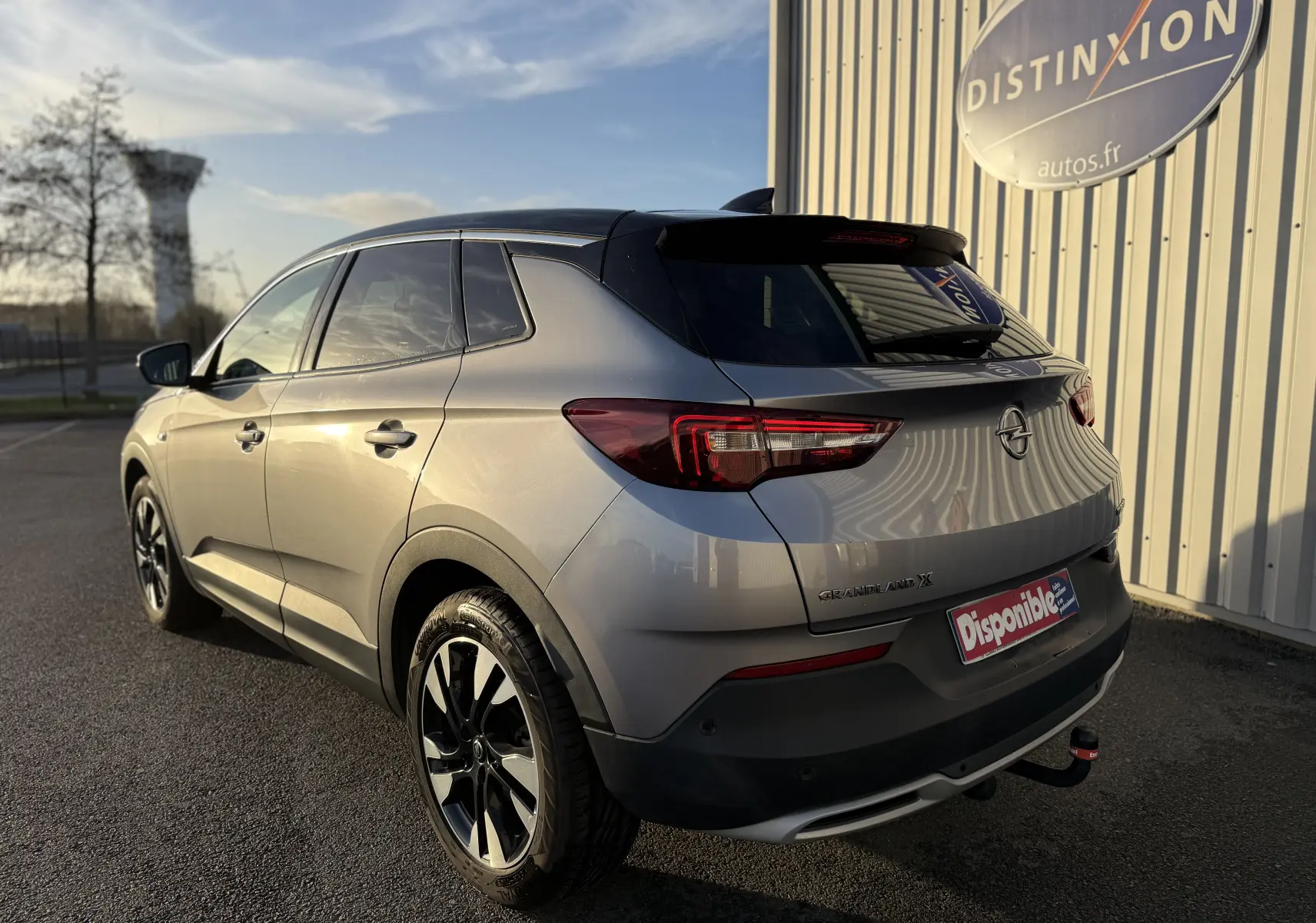 Opel Grandland X gris quartz vu en 3/4 arrière droit, avec jantes noires et toit noir contrastant.