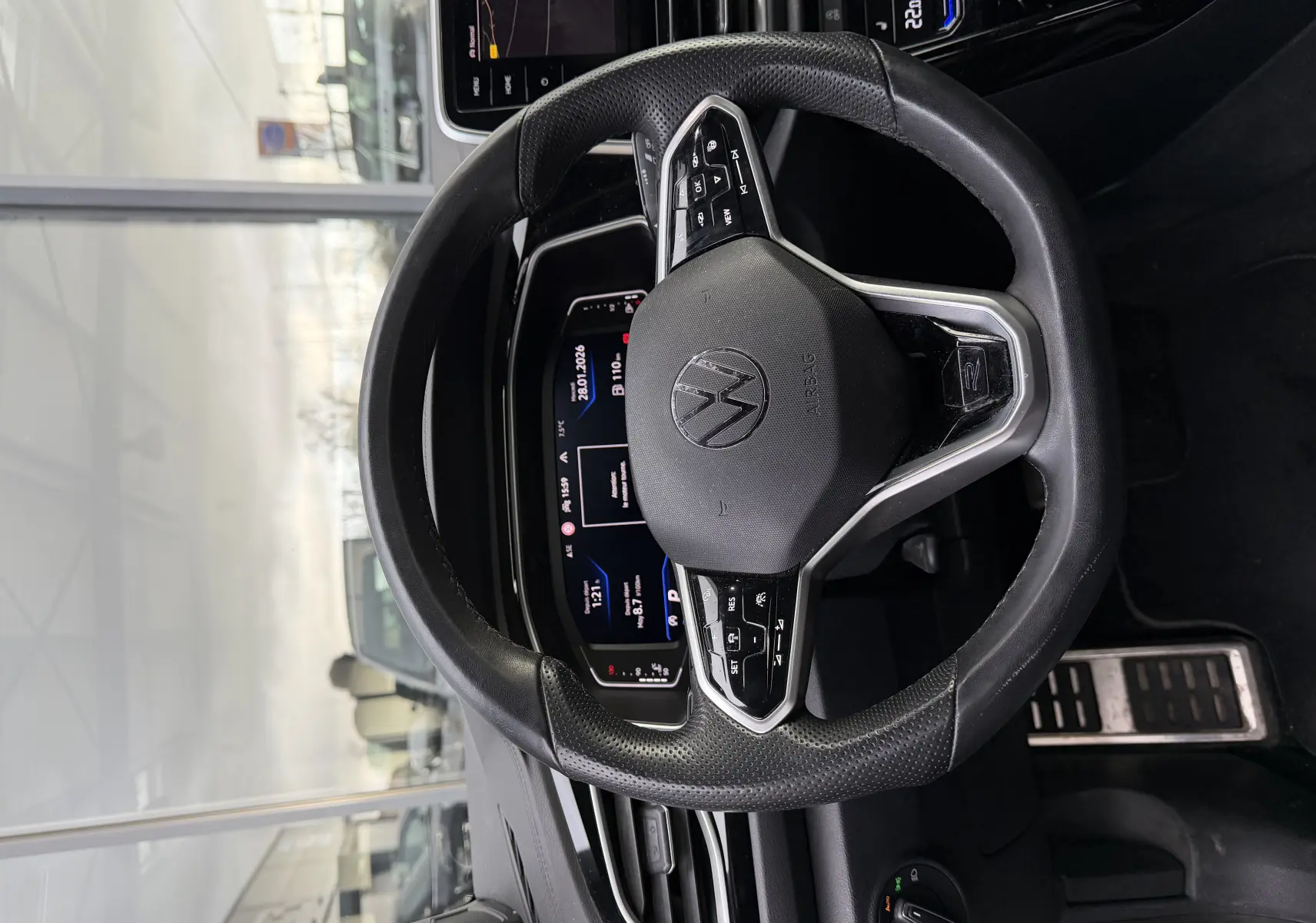 Vue rapprochée du volant multifonction noir du Volkswagen T-Roc Cabriolet blanc, avec tableau de bord numérique en arrière-plan.