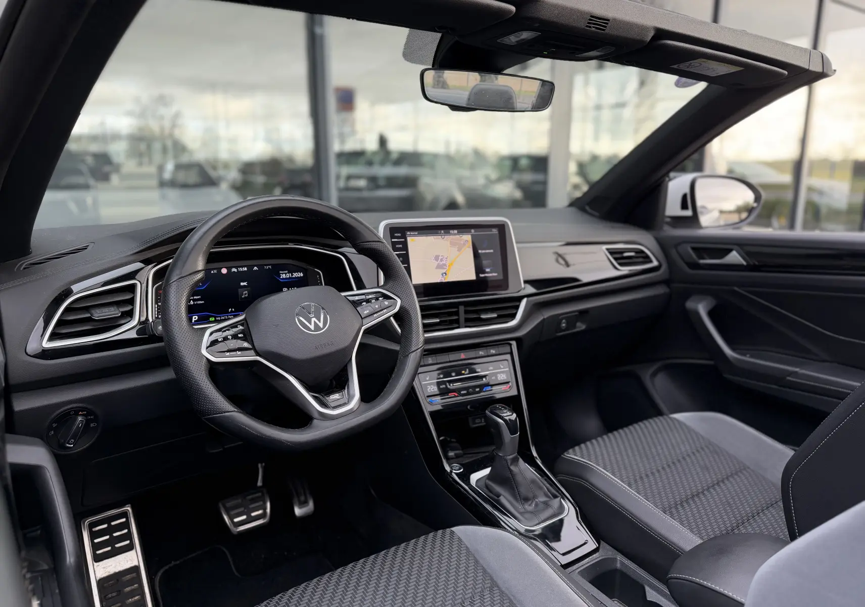 Vue intérieure côté conducteur du Volkswagen T-Roc Cabriolet blanc 2022, avec tableau de bord numérique et écran central tactile.