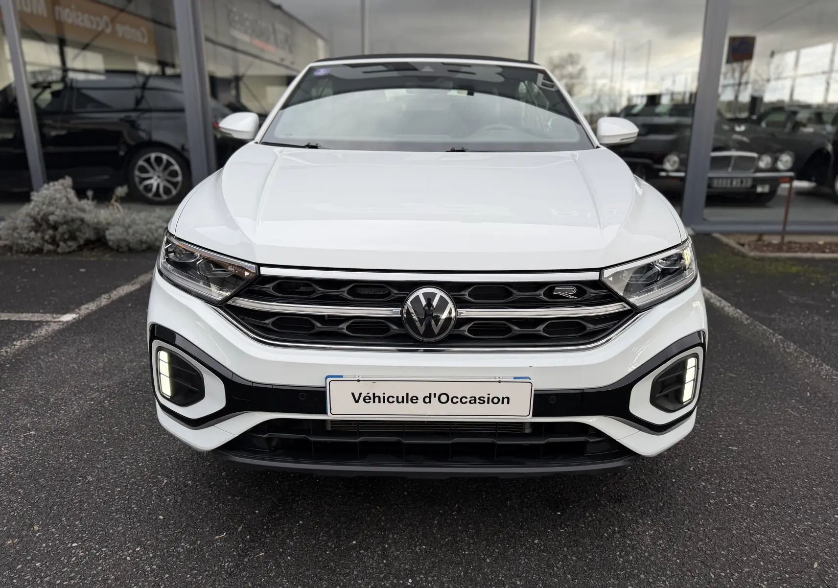 Vue frontale d'un Volkswagen T-Roc Cabriolet blanc 2022 avec calandre R-Line et feux LED allumés.