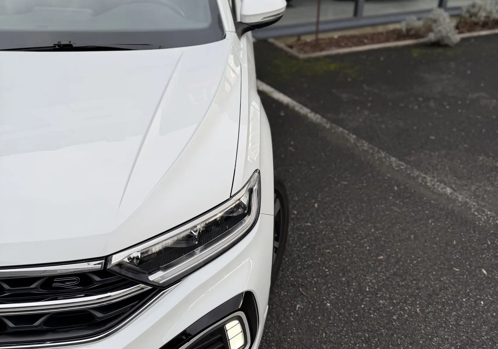 Vue 3/4 avant droit du Volkswagen T-Roc Cabriolet blanc 2022, mettant en valeur ses phares LED et la calandre R-Line.