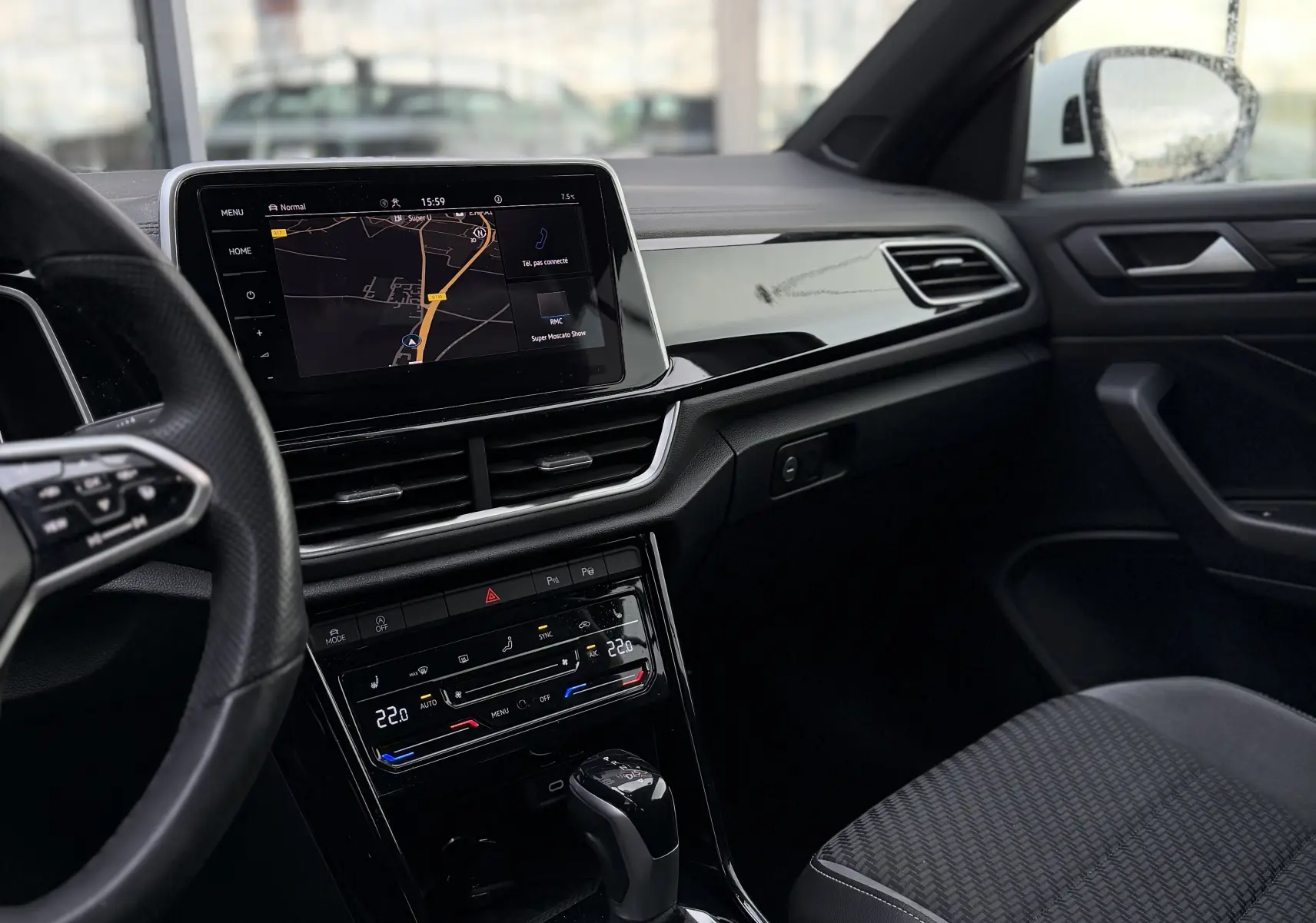 Vue intérieure côté conducteur du Volkswagen T-Roc Cabriolet blanc 2022, avec écran tactile et levier de boîte automatique.