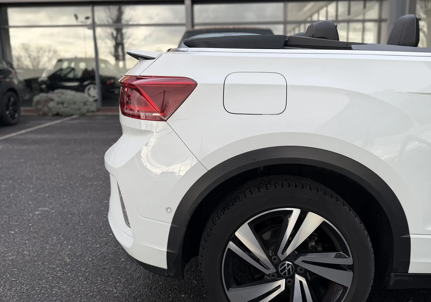 Vue arrière côté gauche d'un Volkswagen T-Roc Cabriolet blanc 2022 avec jante alliage et capote ouverte.
