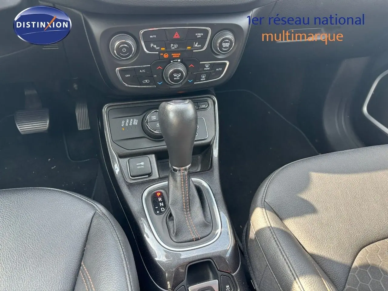 Vue rapprochée de la console centrale du Jeep Compass hybride rechargeable 2021, avec levier de vitesse automatique et sièges cuir noirs.