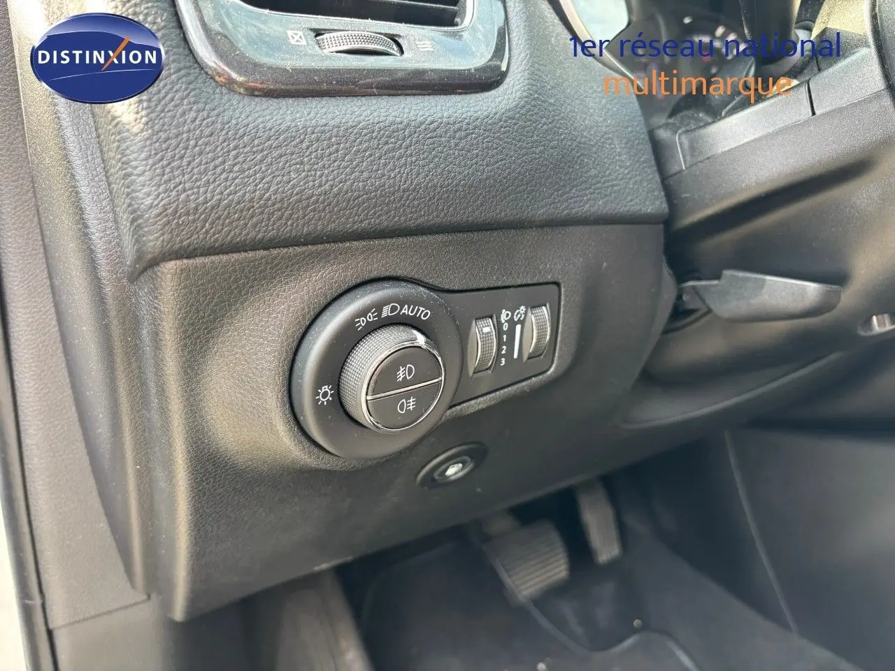 Gros plan sur le bouton de réglage des phares à gauche du tableau de bord du Jeep Compass blanc hybride rechargeable.