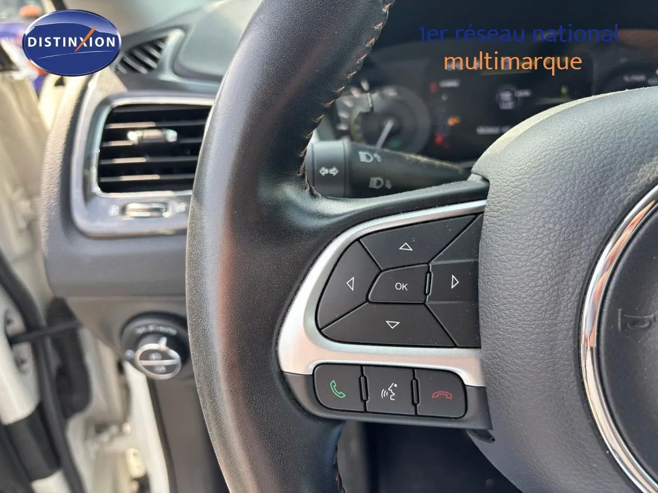 Gros plan sur le volant côté gauche du Jeep Compass blanc 2021, avec commandes intégrées et tableau de bord partiel visible.