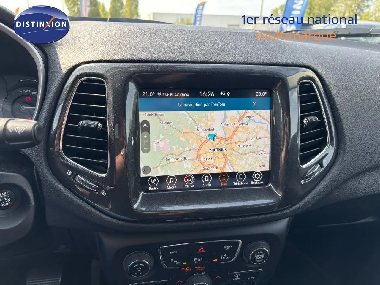 Vue rapprochée du tableau de bord du Jeep Compass blanc 2021, mettant en valeur l’écran tactile avec navigation GPS active.