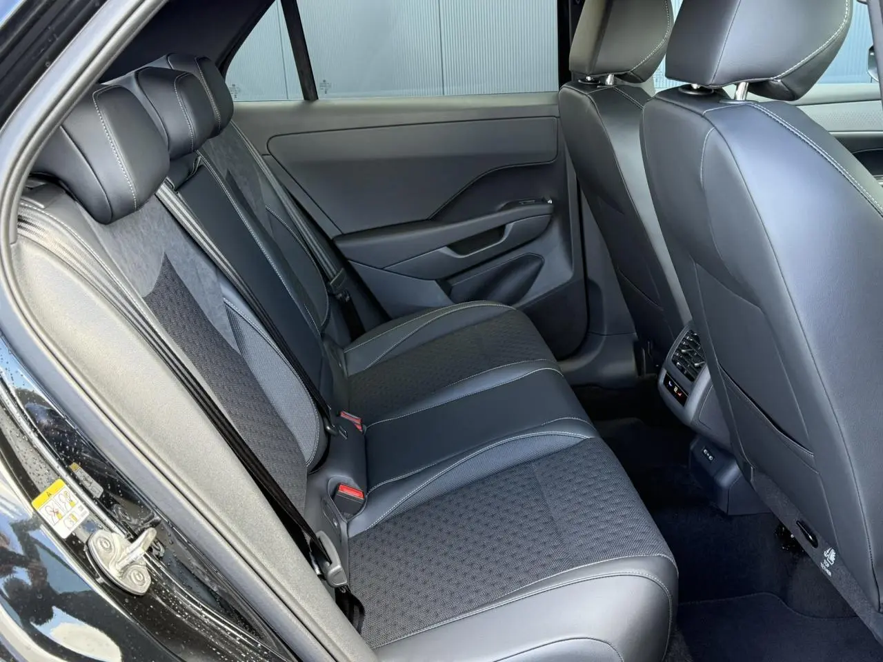 Vue côté gauche de l'intérieur arrière du Volkswagen T-Roc noir Ébène, avec sièges en tissu et cuir R-Line.