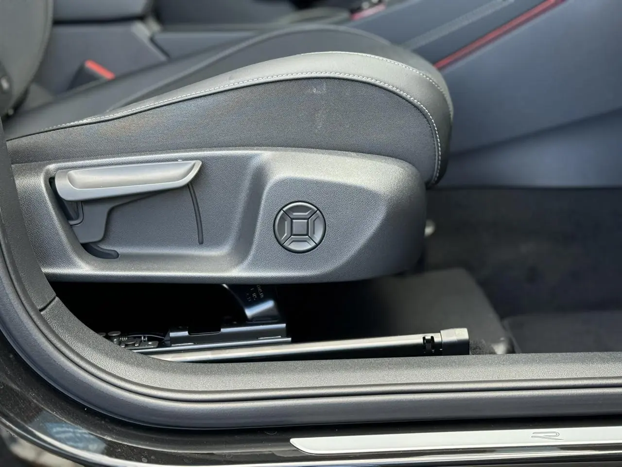 Gros plan sur le réglage manuel du siège avant côté gauche du Volkswagen T-Roc noir Ébène, intérieur sobre.