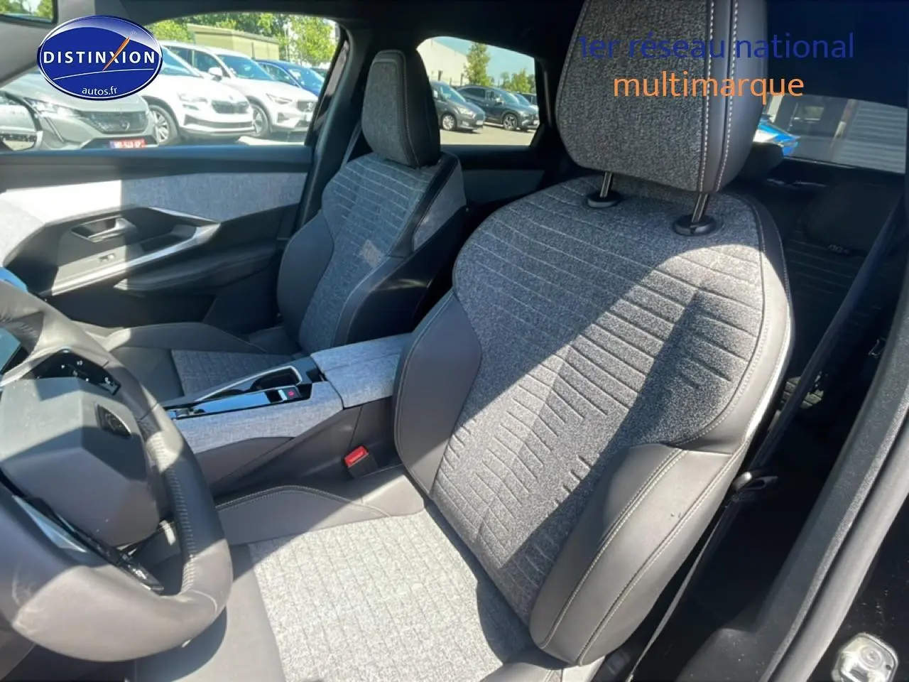 Vue intérieure côté conducteur du Peugeot 3008 noir 2025, sièges tissu gris avec surpiqûres et volant cuir multifonction.