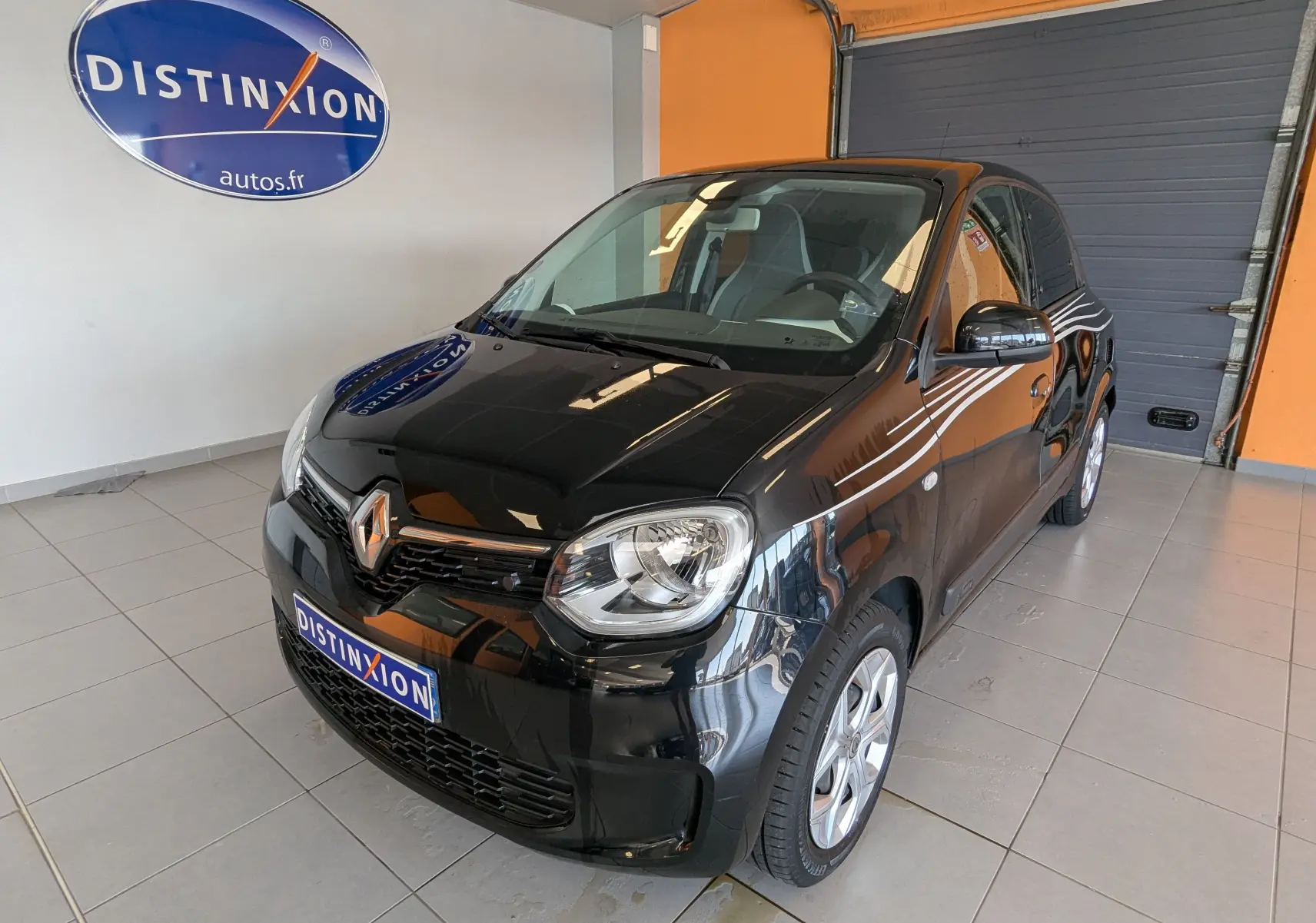 Renault Twingo III noir vue 3/4 avant droit en intérieur, avec logo distinctif sur calandre et jantes argentées.
