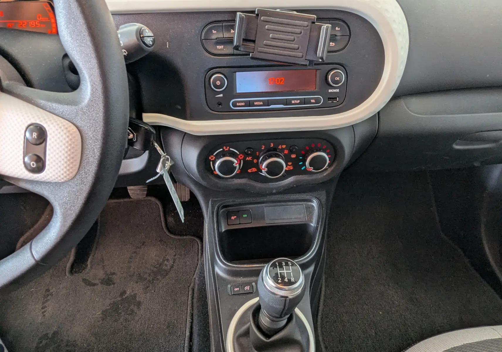 Vue intérieure centrée sur la console centrale et levier de vitesses manuel d'une Renault Twingo III noire de 2019.