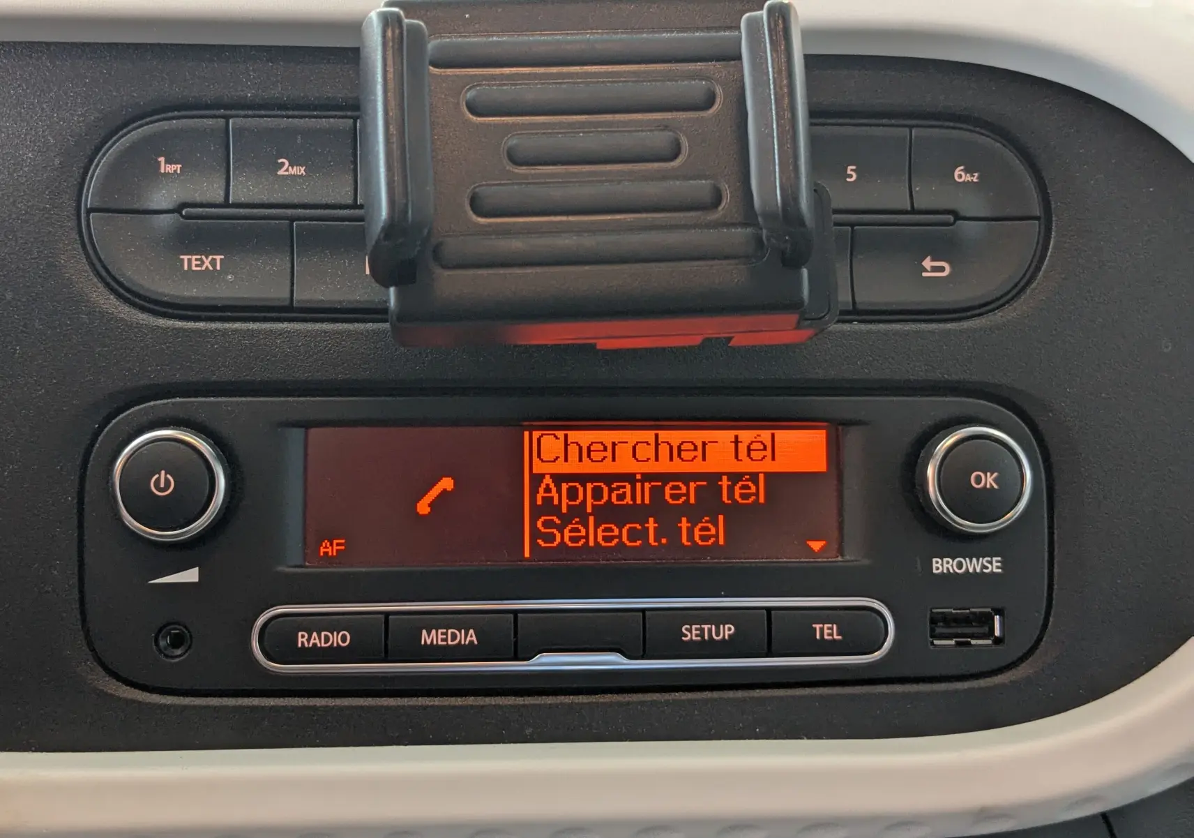 Tableau de bord de Renault Twingo III noir, affichage orange du système multimédia avec options téléphone visibles.