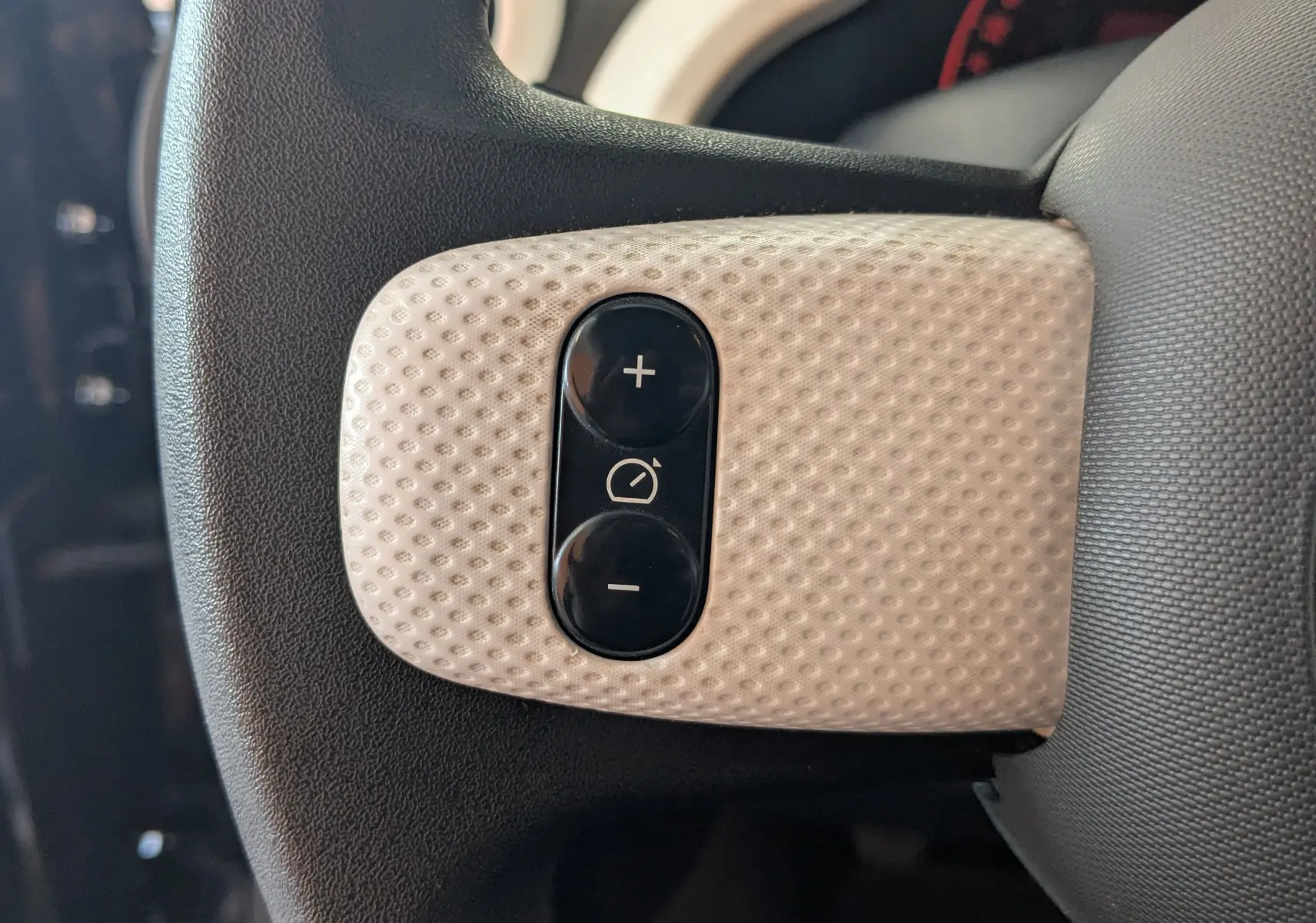 Gros plan sur les commandes de régulateur de vitesse sur le volant noir et beige de la Renault Twingo III 2019.