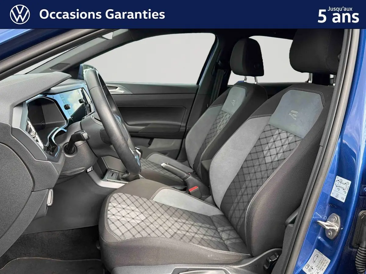 Vue intérieure côté conducteur de la Volkswagen Polo bleue 2025, sièges avant en tissu gris et noir avec surpiqûres contrastées.