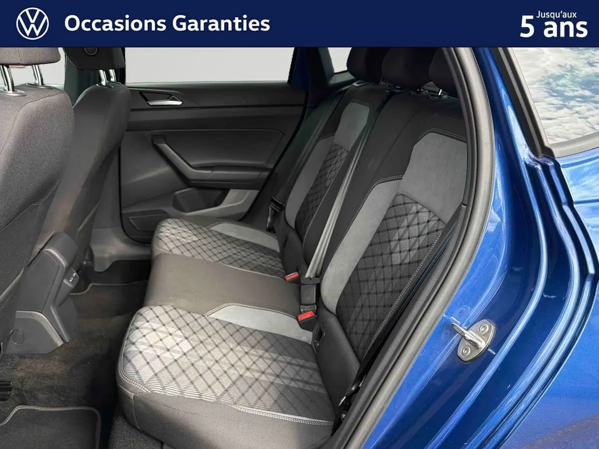 Vue côté droit des sièges arrière en tissu gris à motifs géométriques d'une Volkswagen Polo bleue 2025 avec porte ouverte.