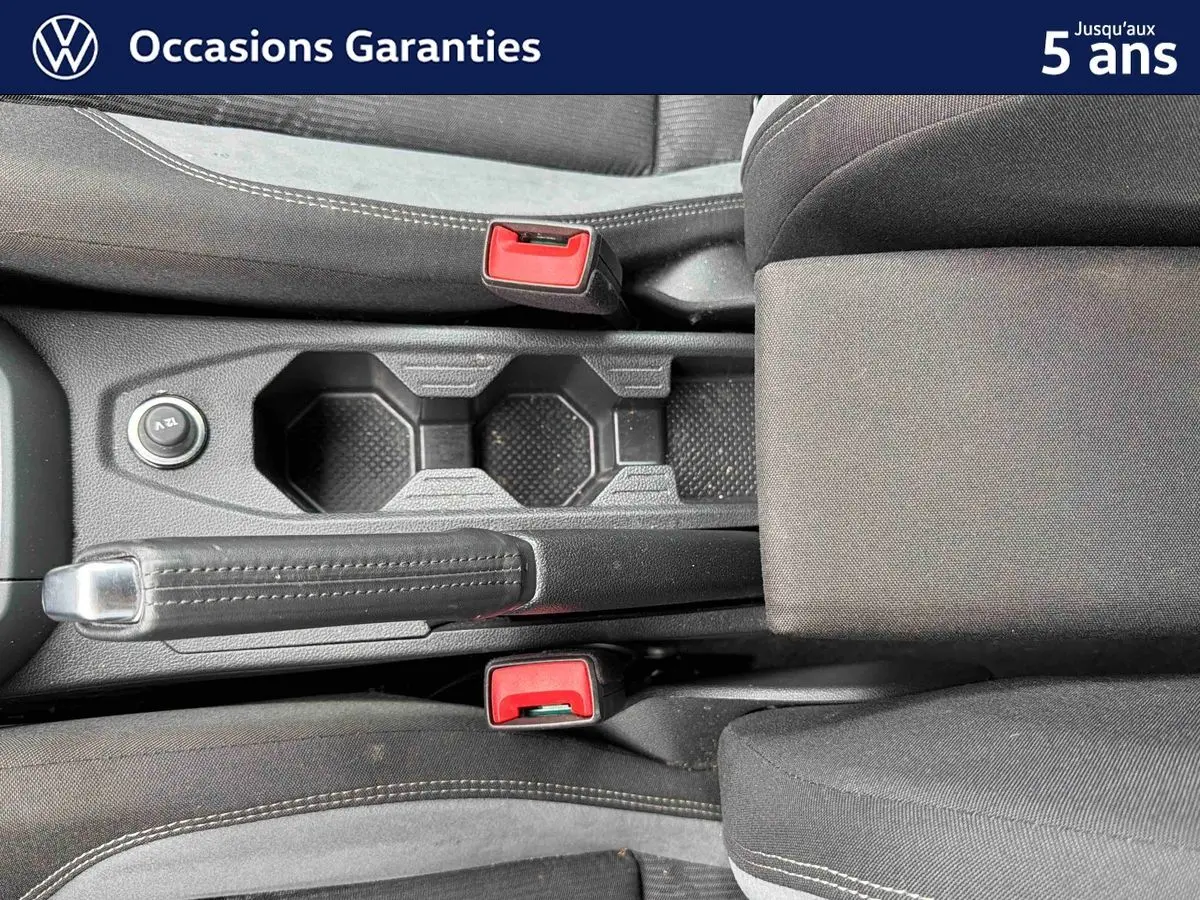 Vue plongeante sur la console centrale noire de la Volkswagen Polo 2025 avec frein à main et deux porte-gobelets.