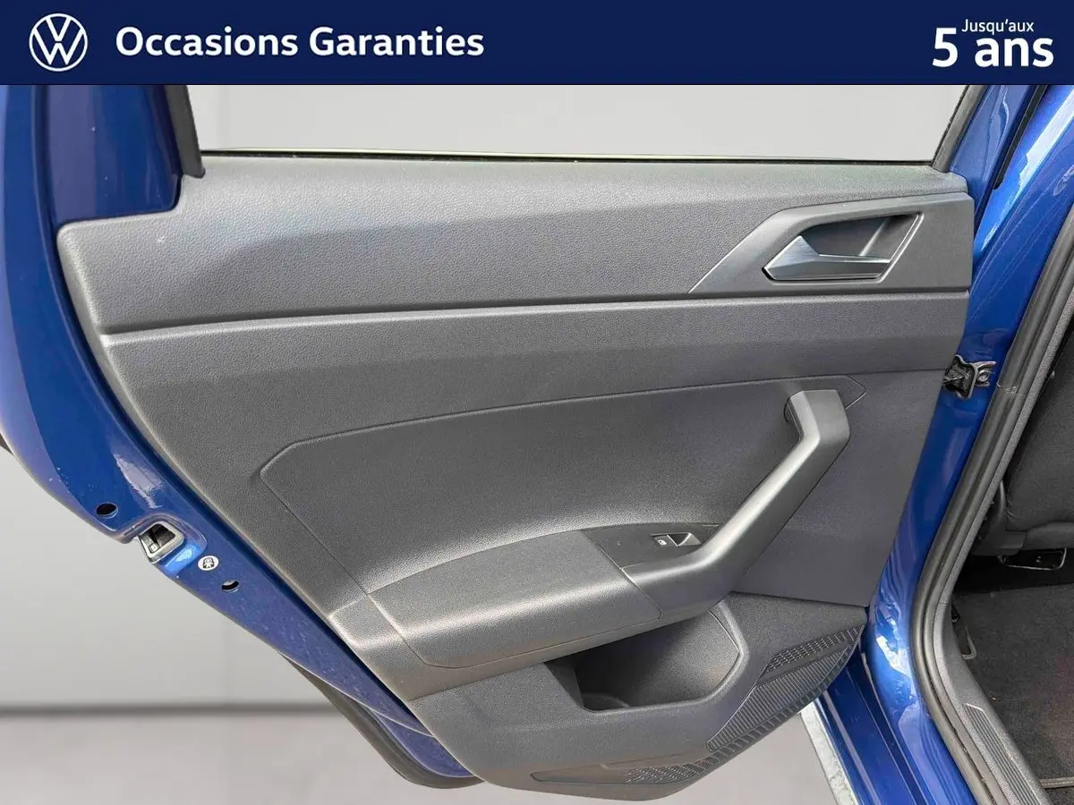 Vue rapprochée de la porte arrière gauche d’une Volkswagen Polo 2025 bleu récif avec garniture intérieure grise.