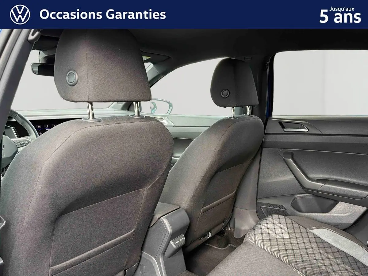Vue intérieure arrière de la Volkswagen Polo 2025, sièges tissu gris foncé avec motifs et portières noires.