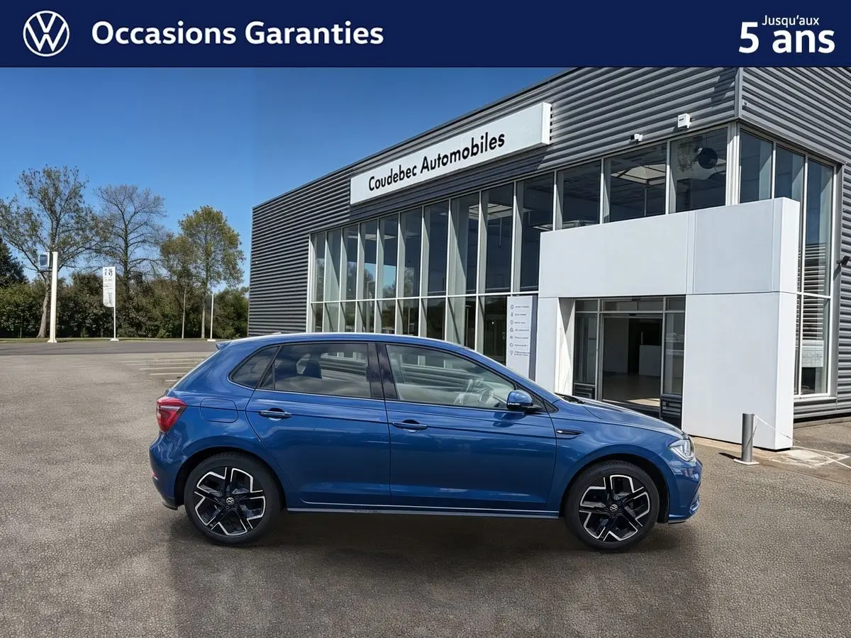 Volkswagen Polo 2025 bleu métallisé vue de profil côté gauche devant un bâtiment de concession.