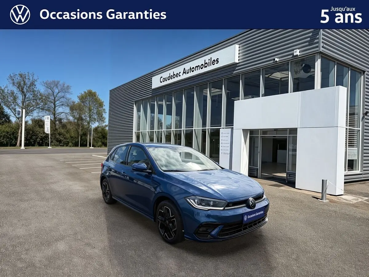 Vue 3/4 avant gauche d'une Volkswagen Polo 2025 bleu récif métallisé avec toit noir devant un concessionnaire.