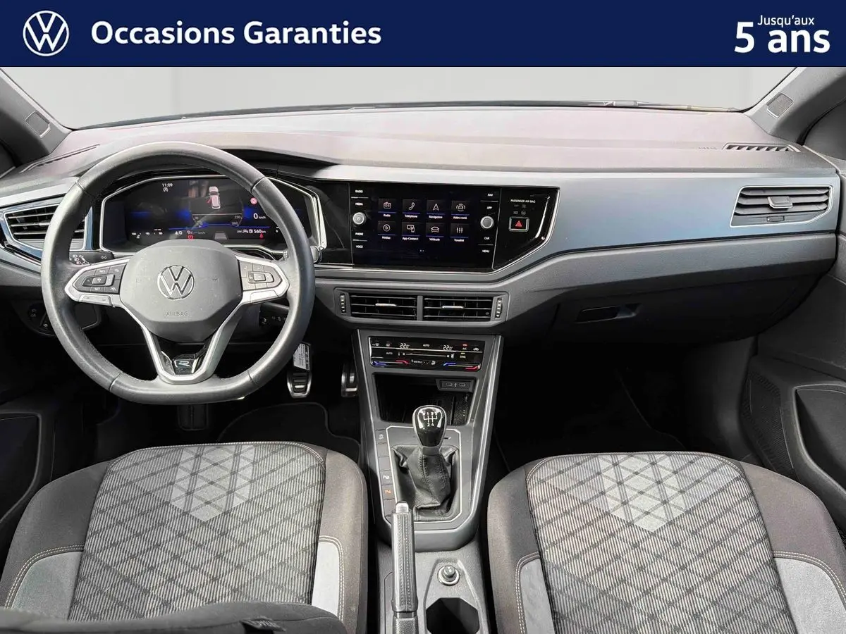 Vue intérieure avant du tableau de bord et volant cuir d’une Volkswagen Polo 2025 avec boîte manuelle et écran tactile central.