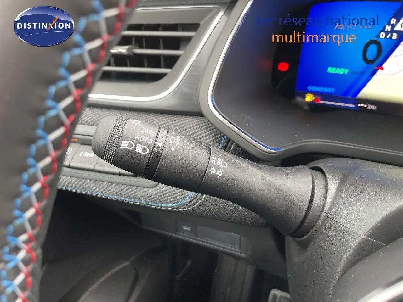 Détail du commodo d’éclairage à gauche du volant, intérieur noir avec surpiqûres bleues du Renault Symbioz gris cassiopée.