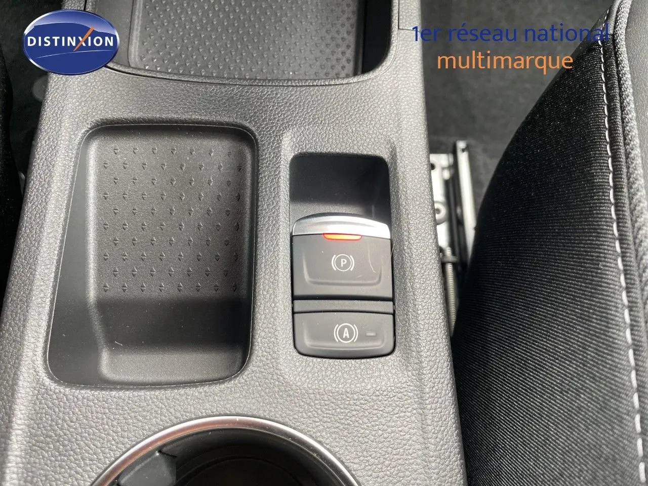 Gros plan sur la console centrale intérieure de la Renault Symbioz gris cassiopée, avec boutons de frein à main et auto hold.