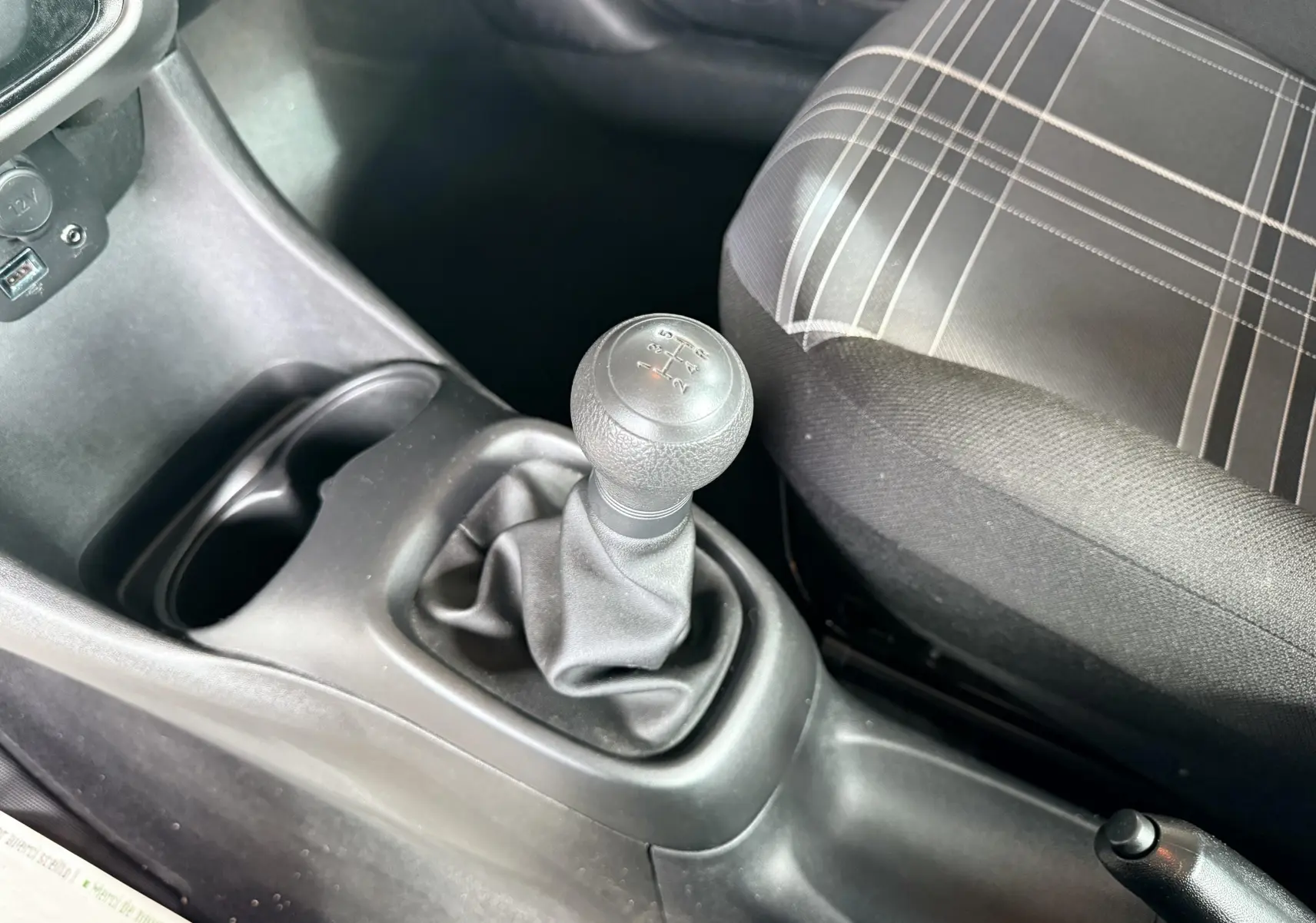 Le levier de vitesses manuel noir et la sellerie tissu gris à motifs à l'intérieur d'une Peugeot 108 2018.