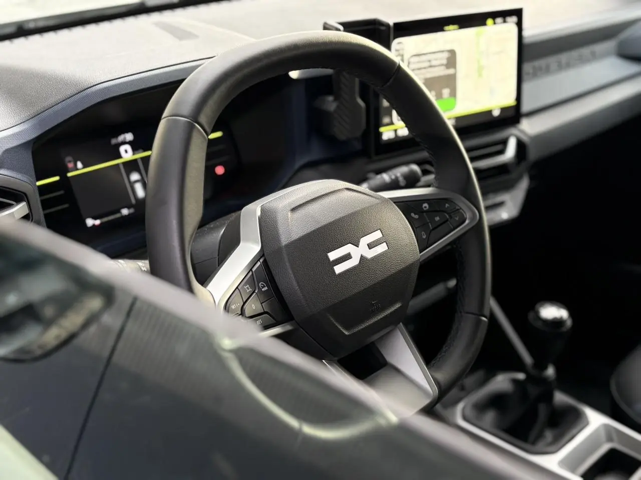Vue rapprochée du volant et tableau de bord digital du Dacia Duster 2024, intérieur noir avec écran tactile.