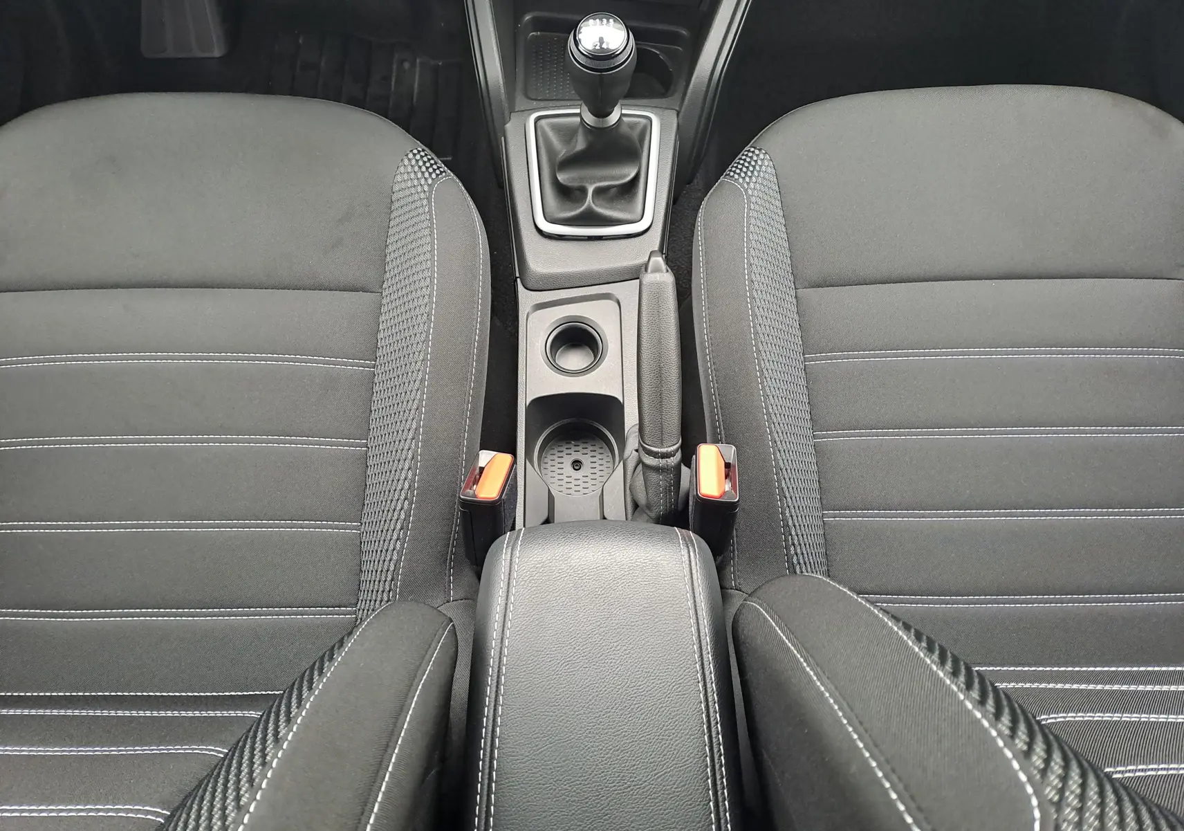 Vue plongeante sur l'intérieur noir du Dacia Duster 2023, montrant la console centrale avec levier de vitesses manuel et accoudoir.