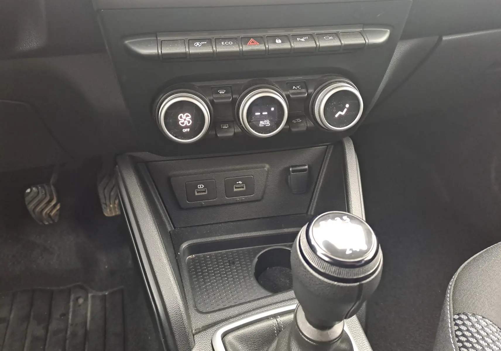 Vue rapprochée de la console centrale du Dacia Duster 2023, avec commandes climatisation et levier de vitesse manuel.