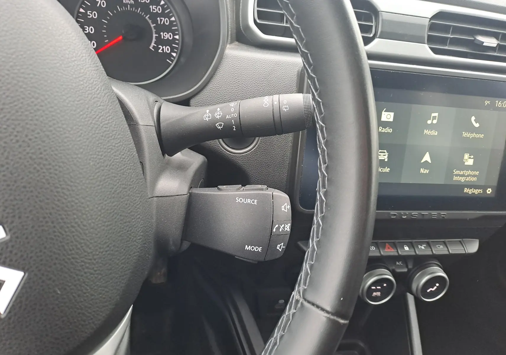Vue rapprochée de l’intérieur du Dacia Duster 2023, volant noir et écran tactile avec menu multimédia visible.