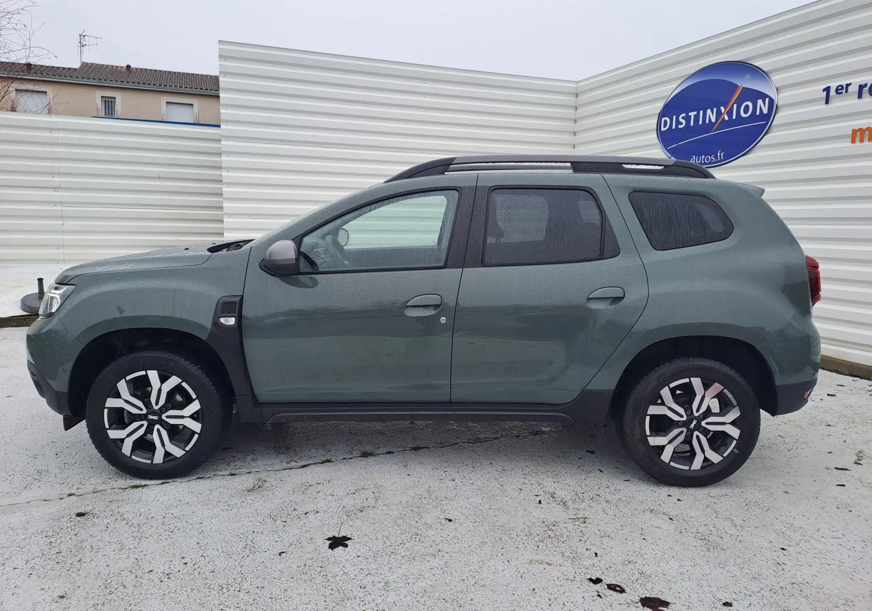 Vue latérale gauche d'un Dacia Duster 2023 kaki avec jantes bi-ton et attelage visible à l'arrière.