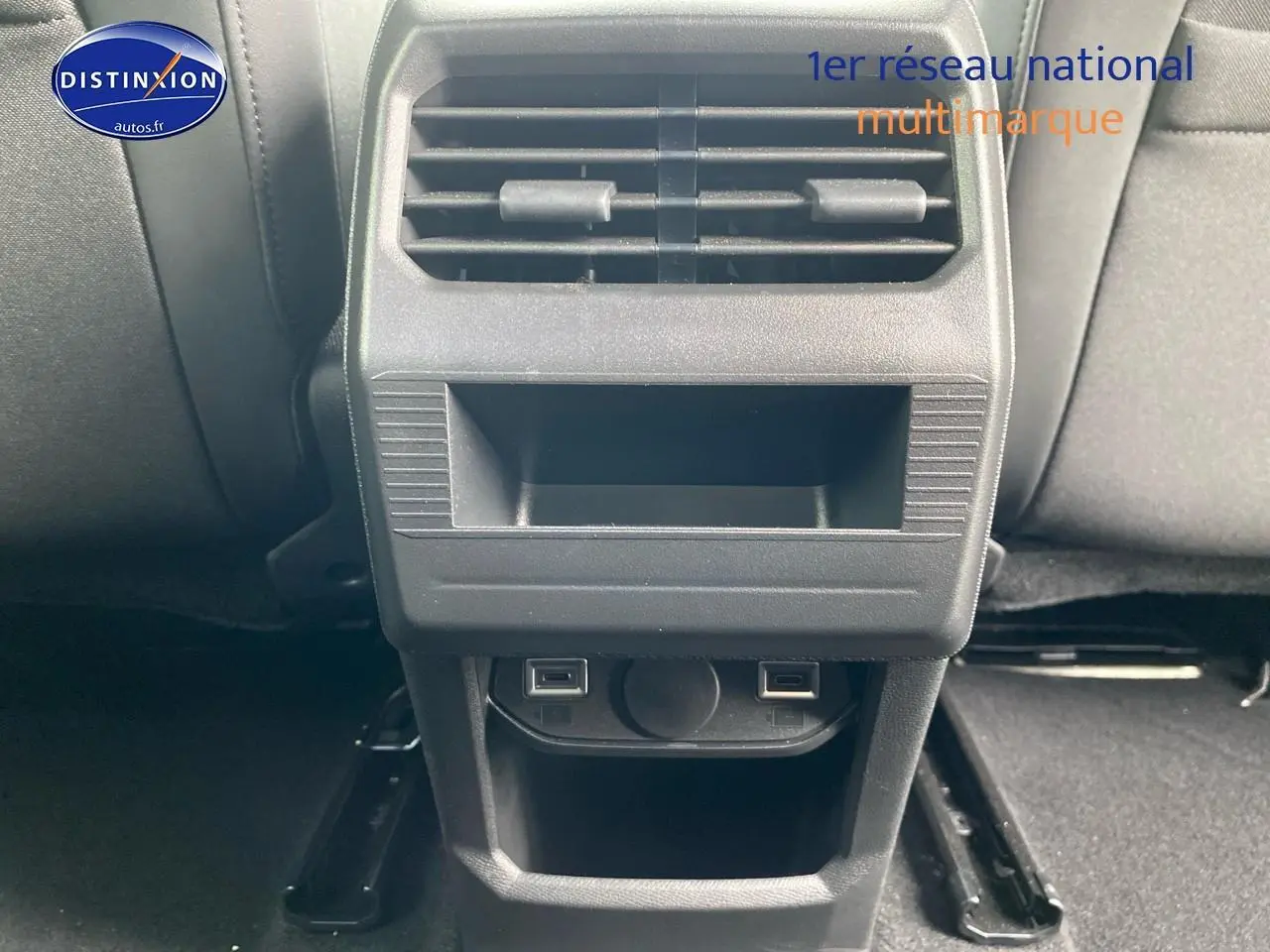 Vue rapprochée de la console arrière noire avec bouches d'aération et prises USB du Peugeot 3008 bleu 2025.