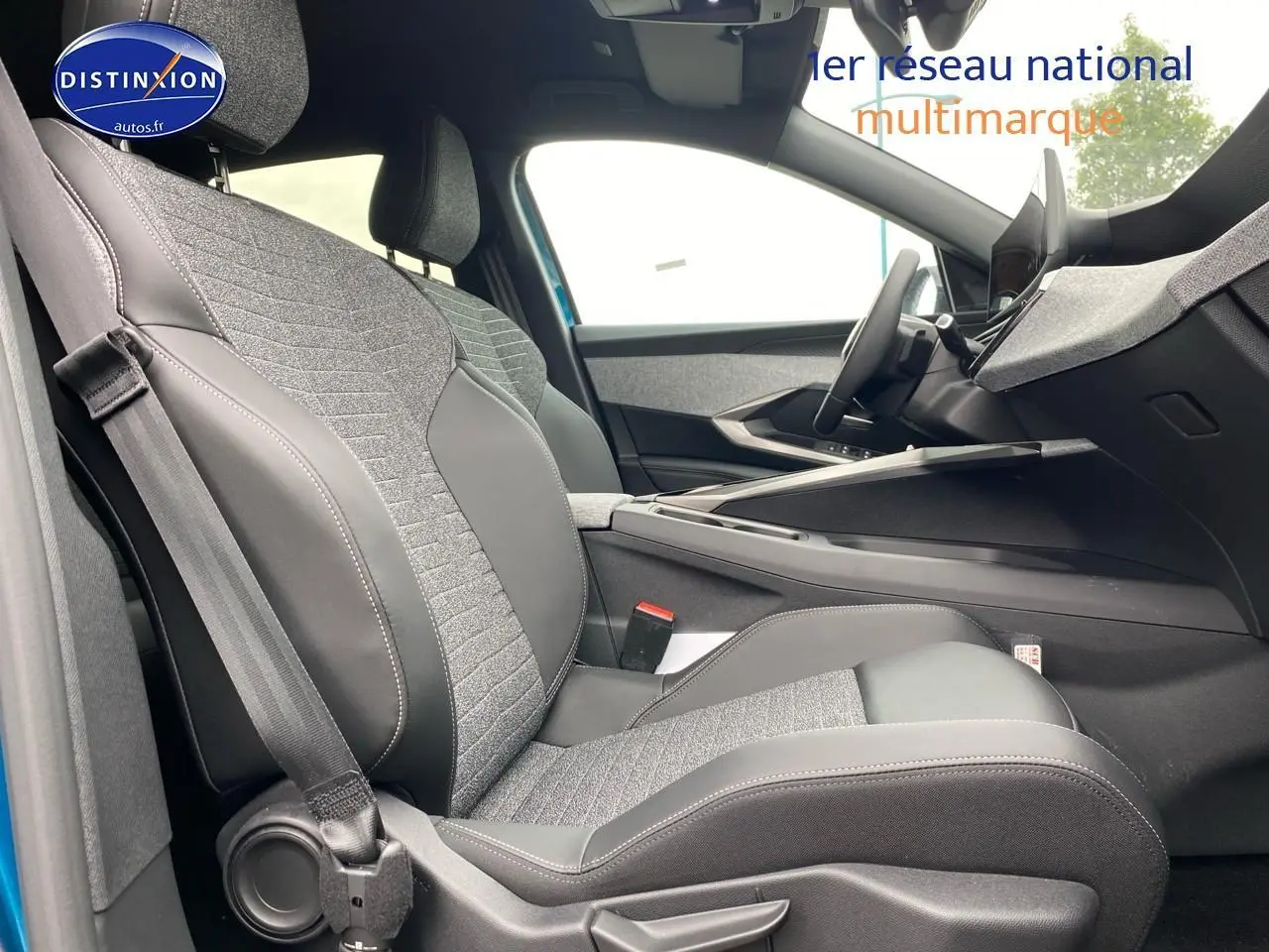 Vue intérieure côté conducteur du Peugeot 3008 bleu 2025, mettant en valeur les sièges tissu et cuir gris avec coutures apparentes.