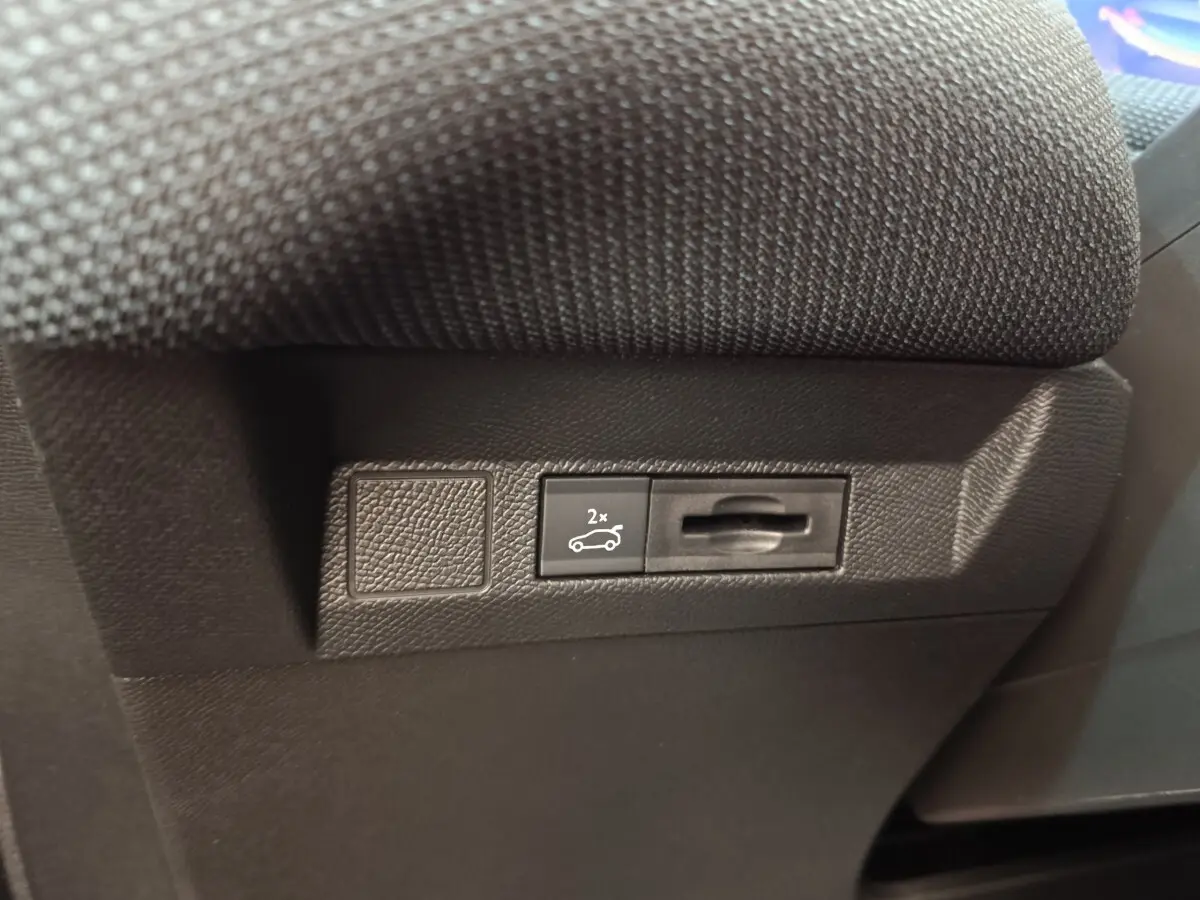 Gros plan sur le bouton d'ouverture du coffre dans l'habitacle noir du Citroën C5 Hybride 2026.