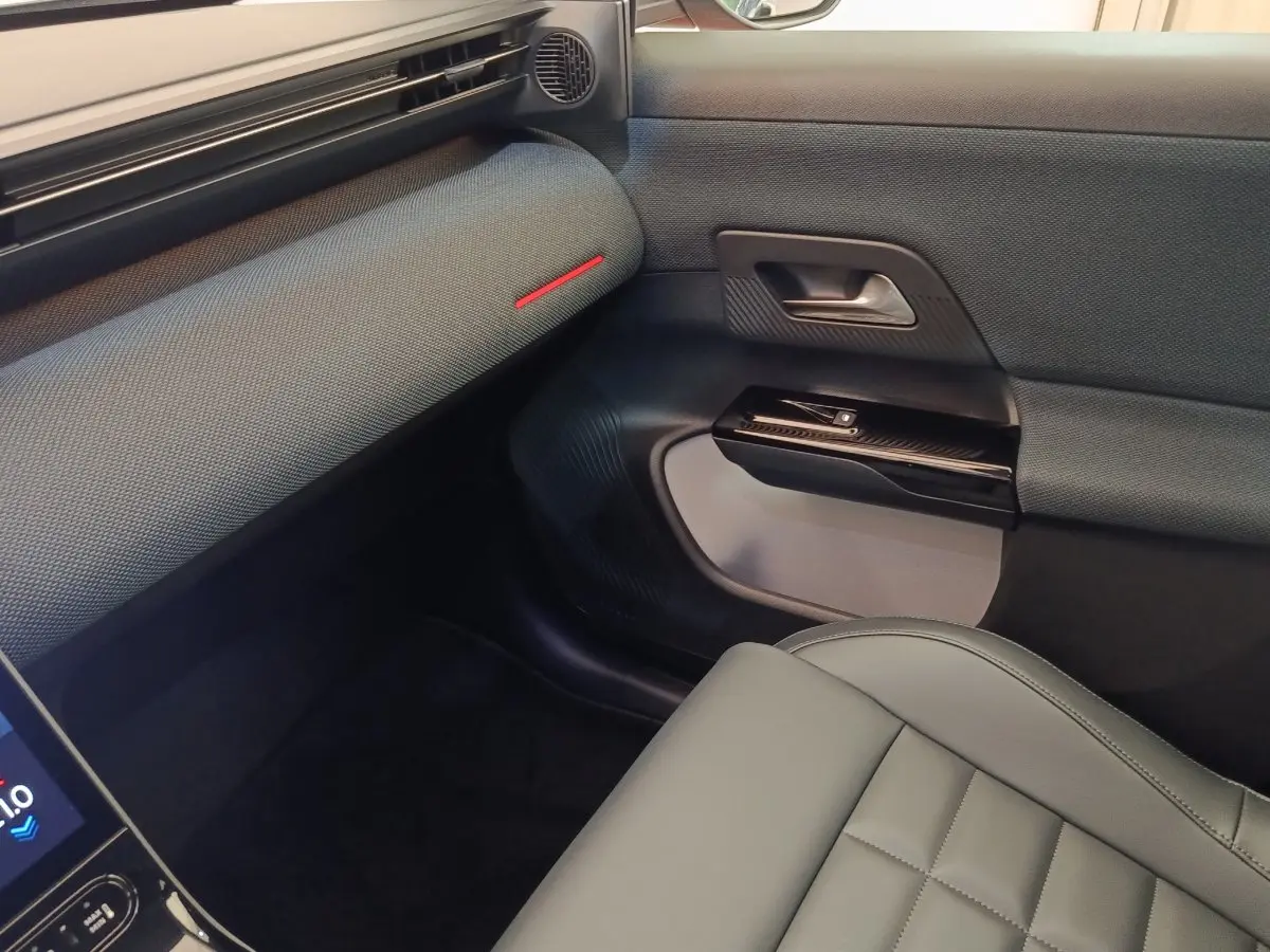 Vue intérieure côté passager avant de la Citroën C5 Hybride 2026, avec sellerie grise et garniture de porte texturée.